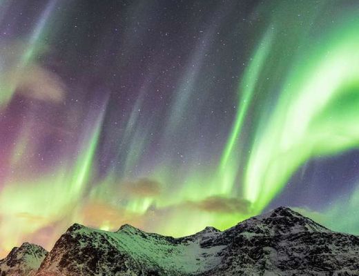 Aurora boreal sobre montanhas nevadas